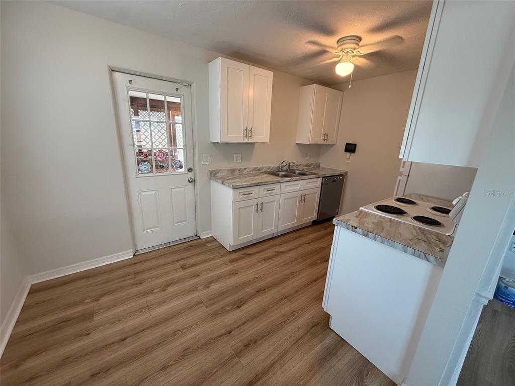 A kitchen features white cabinets, wood-look flooring, a stove, and a door with glass panels — 2217 20TH AVENUE W, BRADENTON, FL
