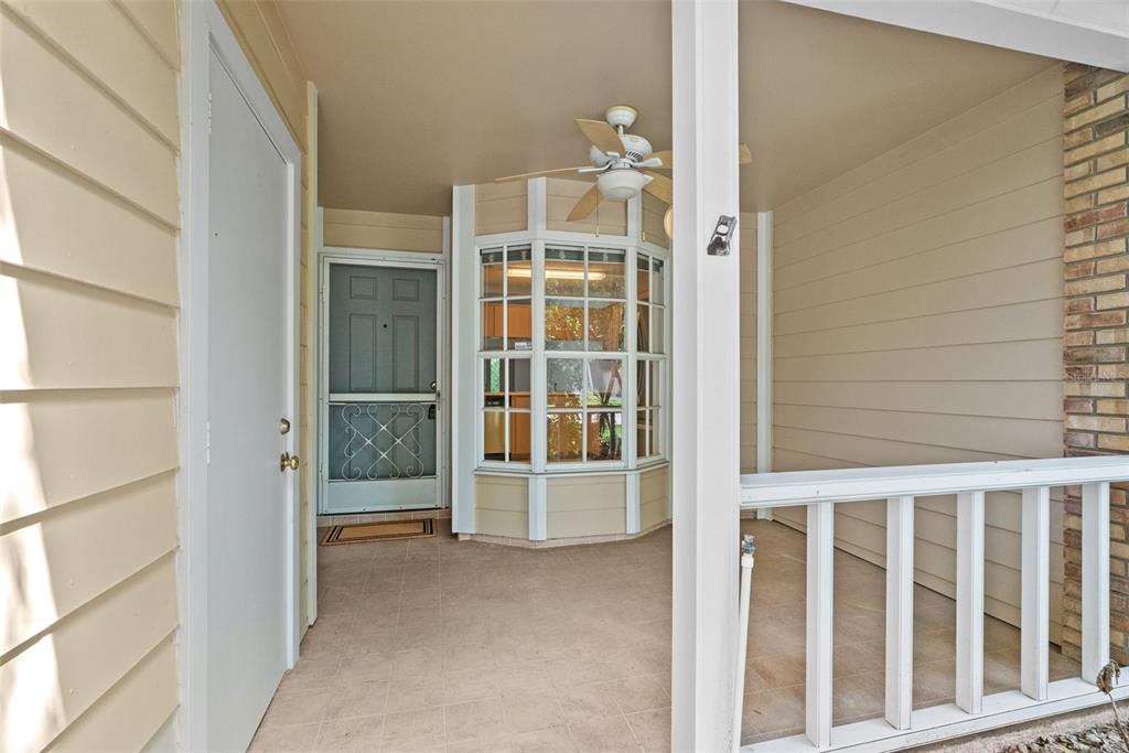 A covered porch features a white front door, a bay window, and a ceiling fan — 6421 REMUS DRIVE, NEW PORT RICHEY, FL