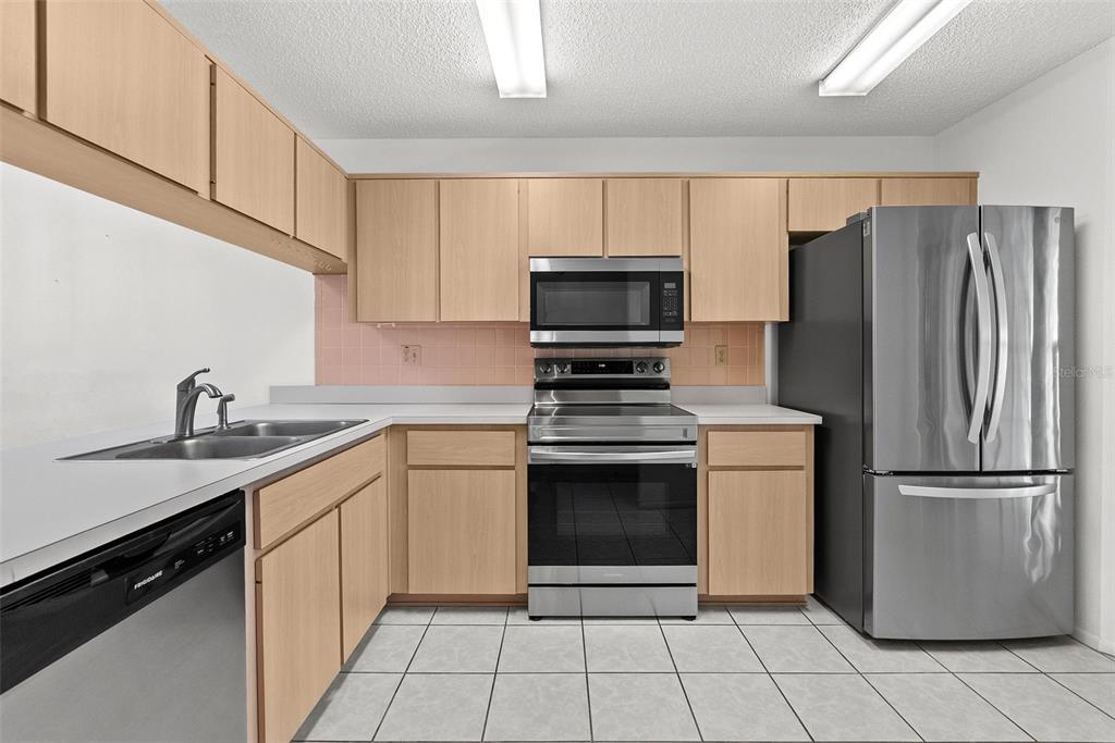 A kitchen features light wood cabinets, stainless steel appliances, and a tiled floor — 6421 REMUS DRIVE, NEW PORT RICHEY, FL