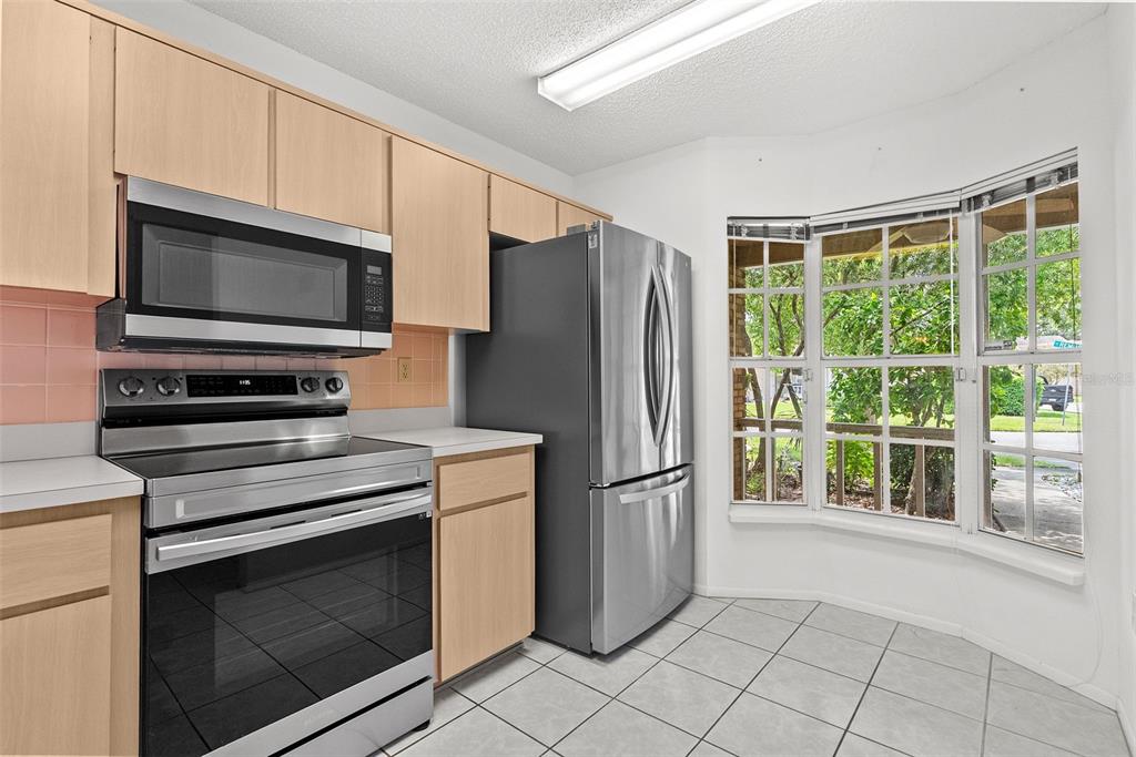A kitchen features light wood cabinets, stainless steel appliances, and a windowed breakfast nook — 6421 REMUS DRIVE, NEW PORT RICHEY, FL