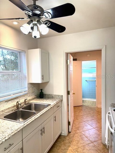 A kitchen features granite countertops, a double sink, white cabinets, and a ceiling fan — 641 MERRIMAC STREET, DELTONA, FL
