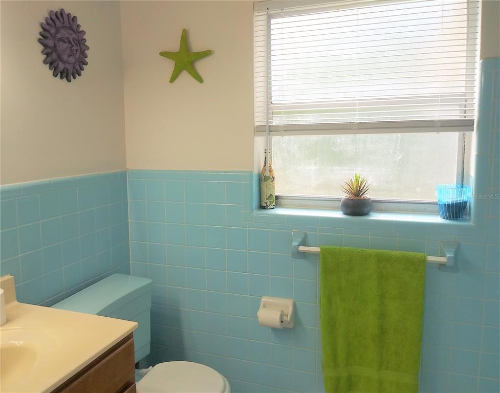 A bathroom features light blue tiled walls, a white vanity, and a window with blinds — 641 MERRIMAC STREET, DELTONA, FL