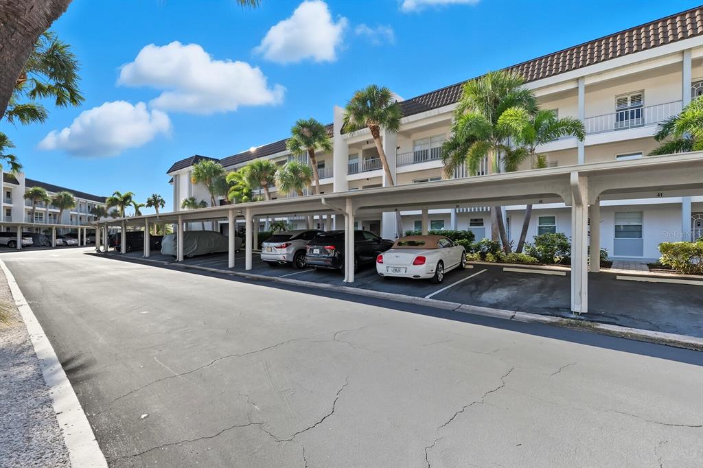 An exterior view of a multi-story apartment building with a covered parking area — 4380 EXETER DRIVE UNIT H202, LONGBOAT KEY, FL