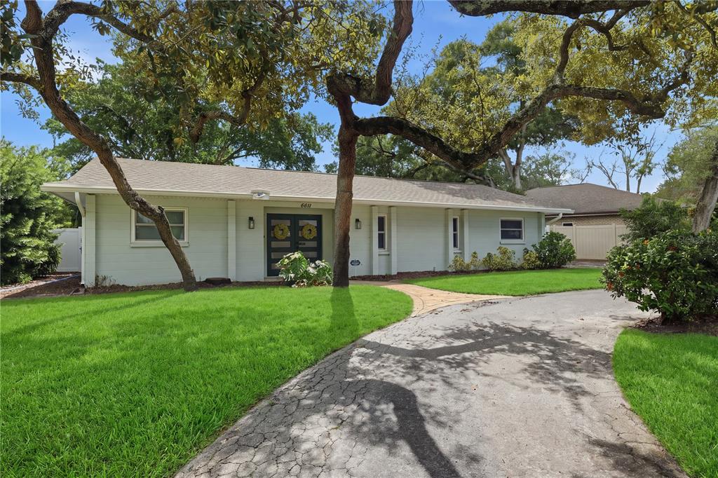 A single-story house with light-colored siding, a dark front door, and a curved driveway — 4411 15TH STREET N, ST PETERSBURG, FL