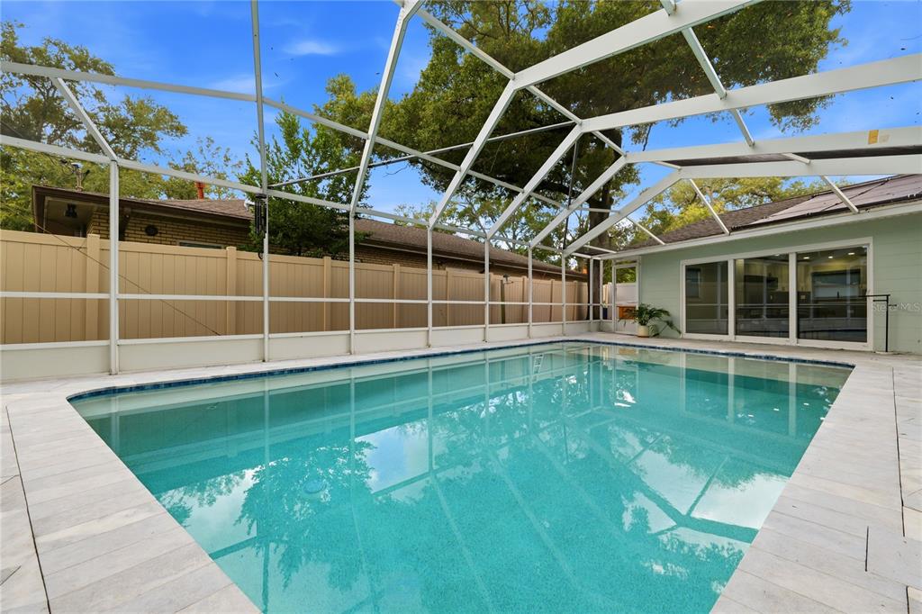 A rectangular swimming pool is enclosed by a white screen cage in a backyard — 4411 15TH STREET N, ST PETERSBURG, FL