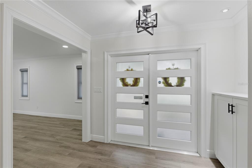 A bright entryway features white double doors with frosted glass panels and a modern light fixture — 4411 15TH STREET N, ST PETERSBURG, FL