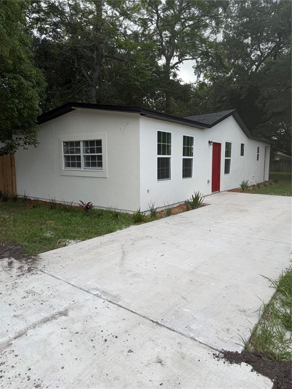 A white, single-story house with a red front door and a concrete driveway — 1701 E BAY STREET, WINTER GARDEN, FL
