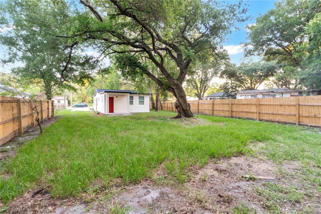 A backyard with a grassy lawn, a large tree, and a small white house — 1701 E BAY STREET, WINTER GARDEN, FL