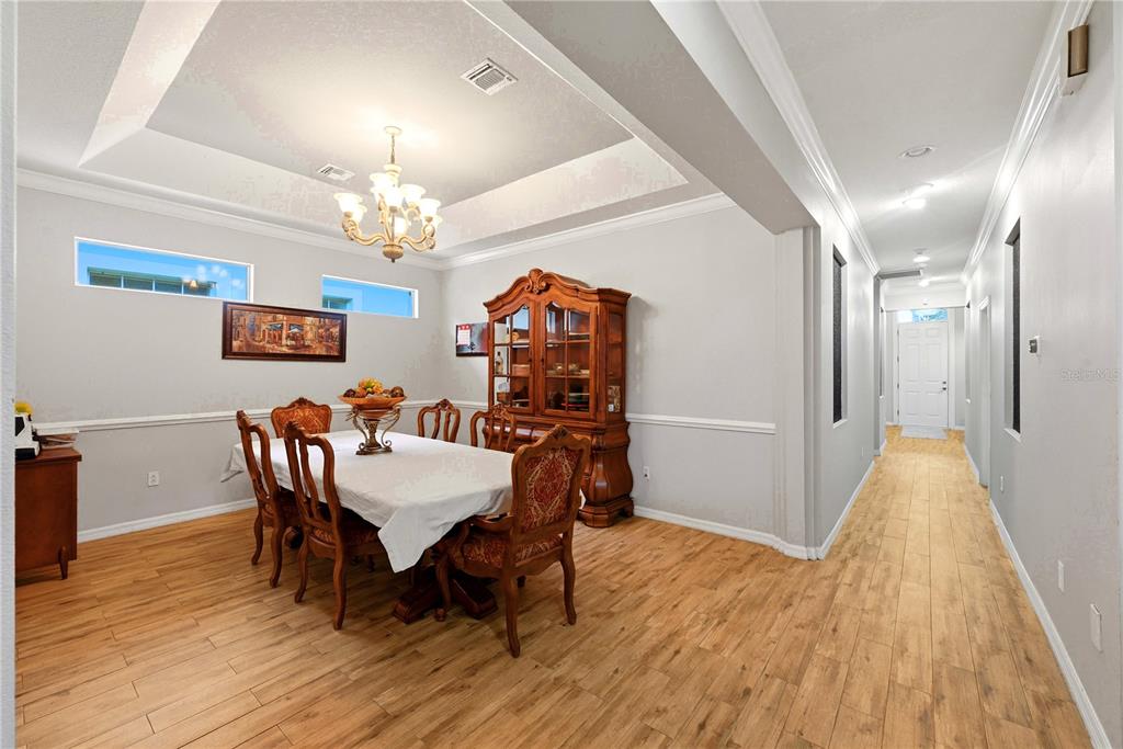 A dining room with a tray ceiling, wood-look tile floors, and a wooden china cabinet — 746 COUNTRY LANE, ORLANDO, FL
