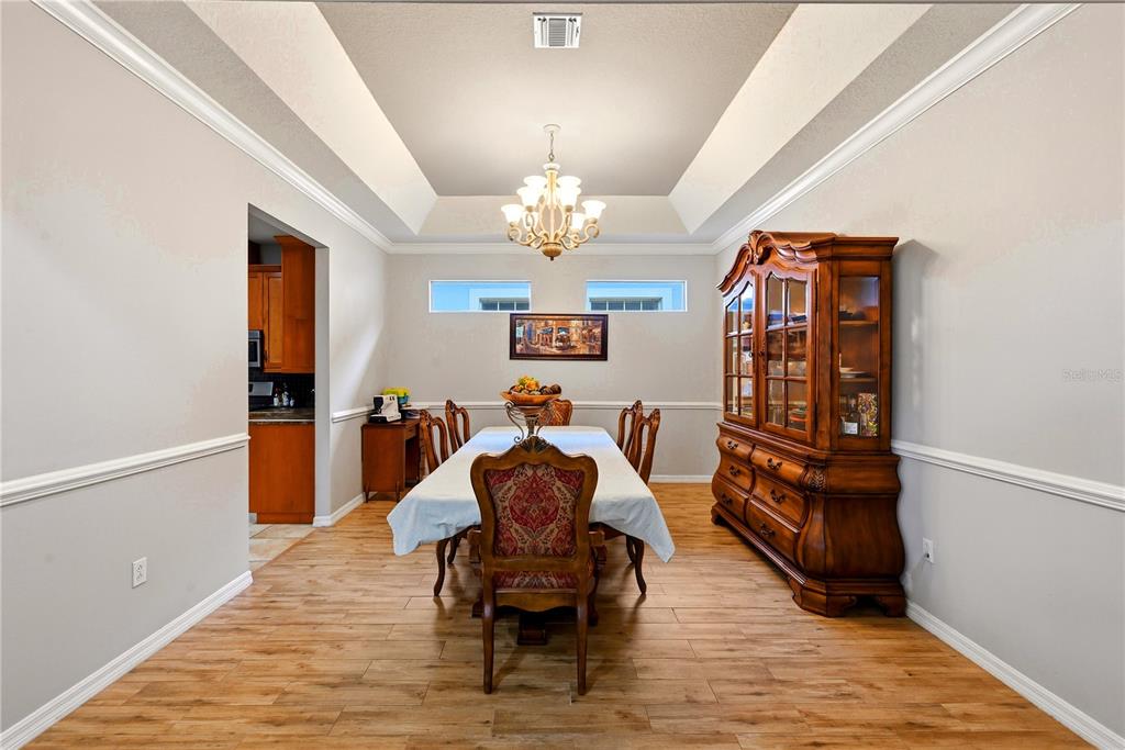 A formal dining room features a tray ceiling, wood-look flooring, and a large wooden hutch — 746 COUNTRY LANE, ORLANDO, FL