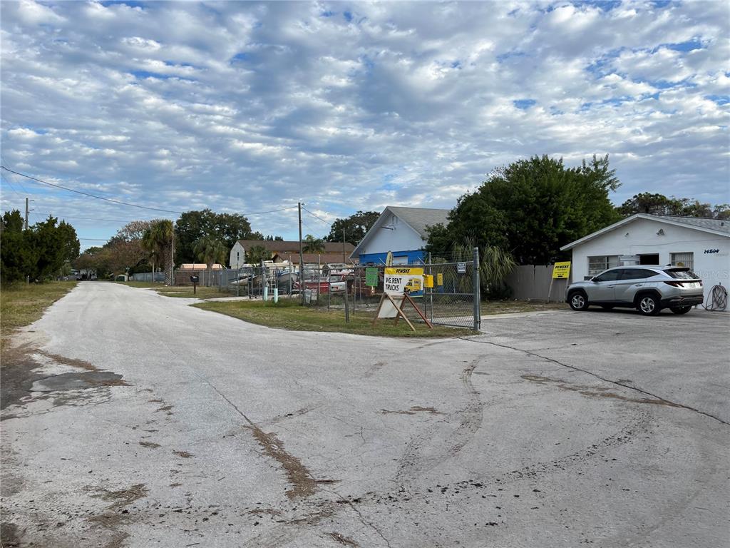 A paved lot features a fenced storage area, a Penske truck rental sign, and a parked SUV — 14602 MARINA DRIVE, HUDSON, FL