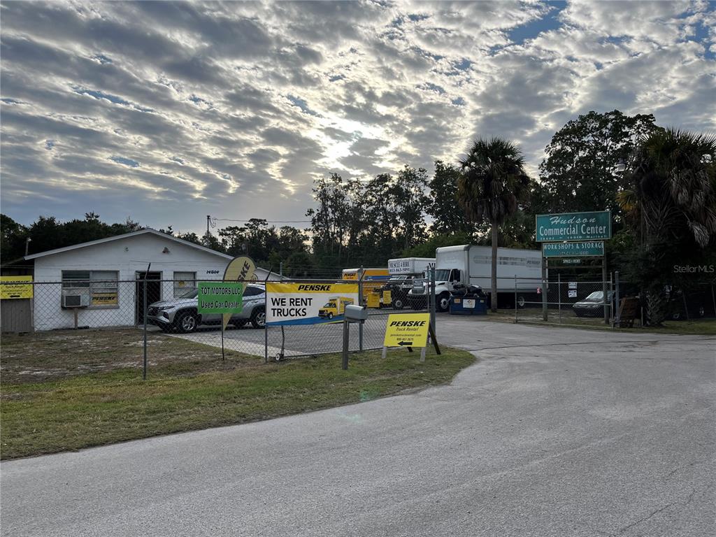 A commercial property with a small building, fenced lot, and several Penske rental trucks — 14602 MARINA DRIVE, HUDSON, FL