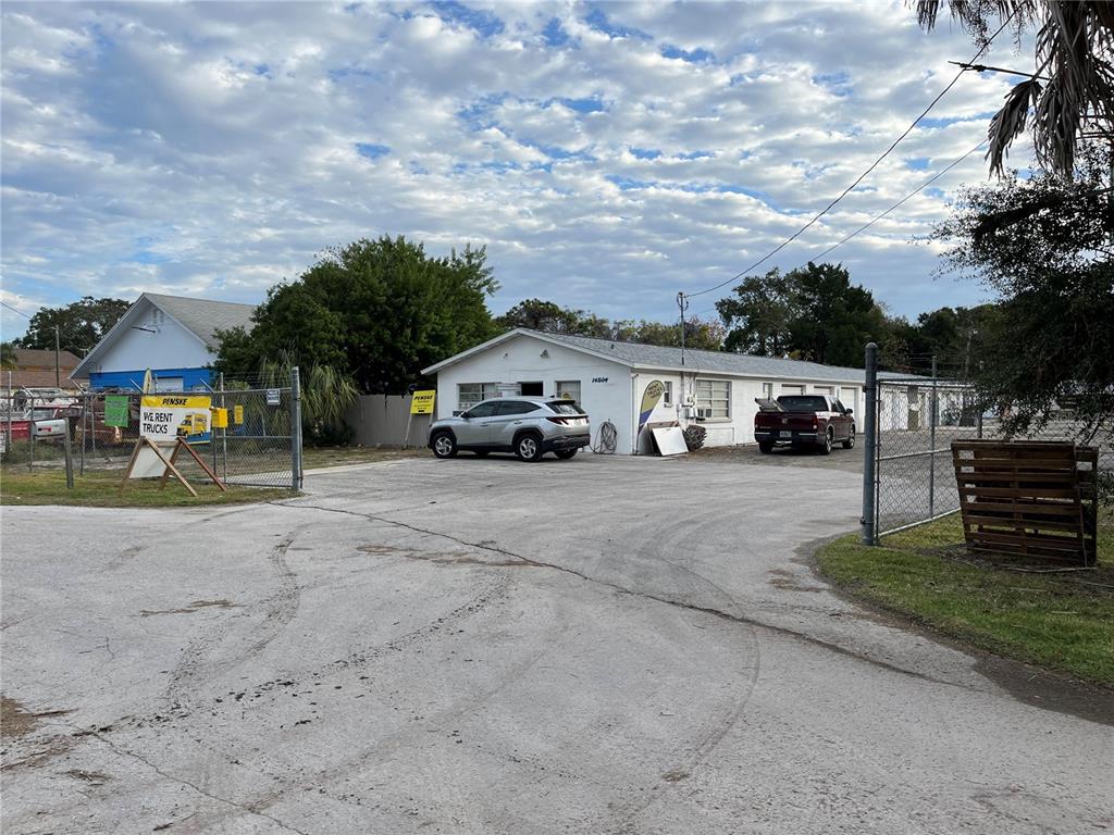 A gravel lot features a single-story commercial building with two parked vehicles and chain-link fencing — 14602 MARINA DRIVE, HUDSON, FL