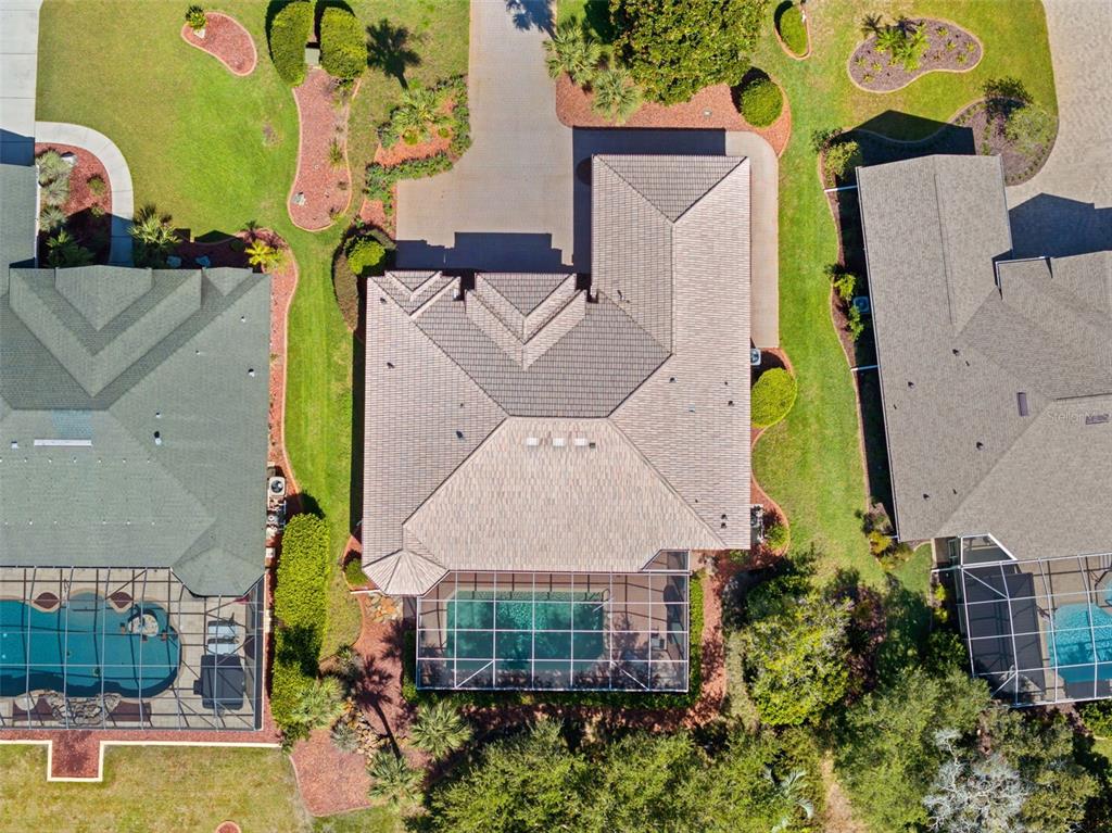 An aerial view shows a house with a tiled roof, a screened pool, and landscaping — 9250 MISSISSIPPI RUN, WEEKI WACHEE, FL