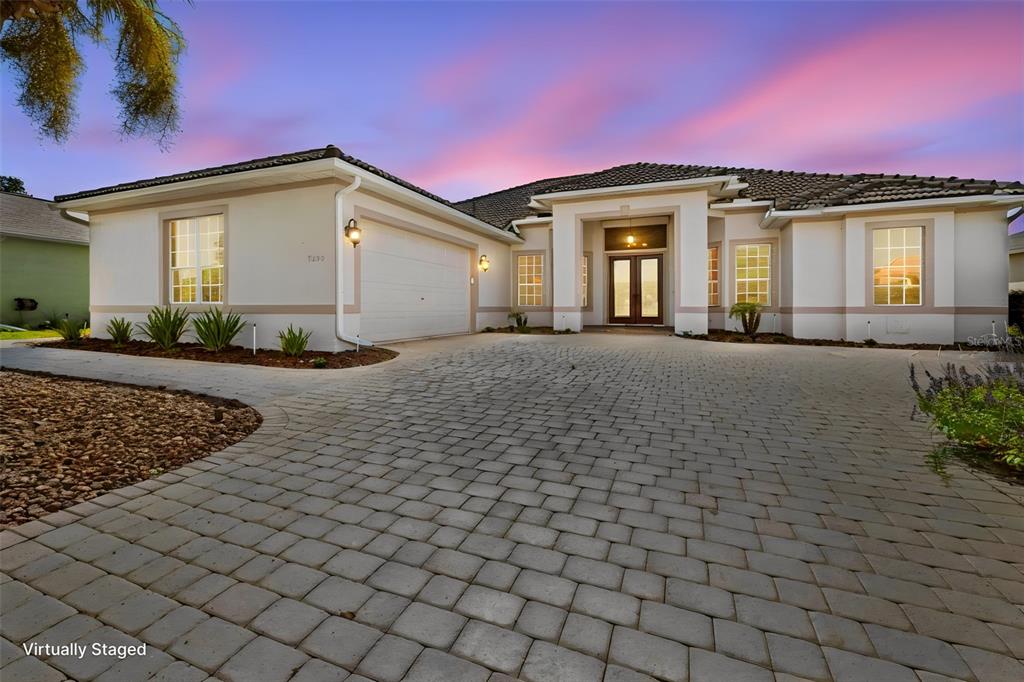 A single-story house with a paved driveway and a two-car garage at sunset — 9250 MISSISSIPPI RUN, WEEKI WACHEE, FL