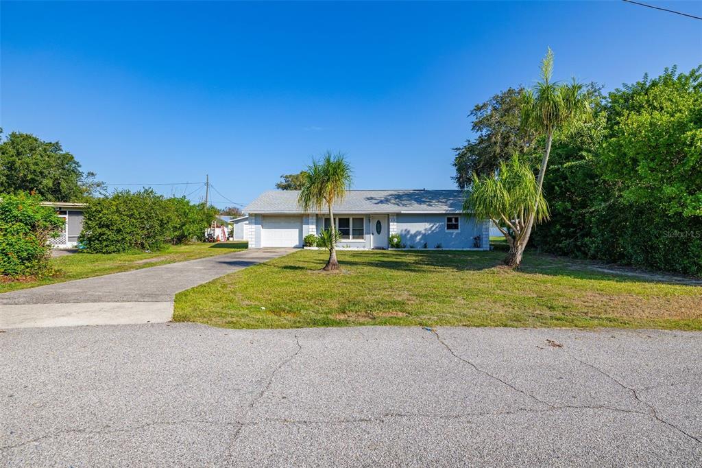 A single-story gray house with a white garage door and a sunset sky overhead — 608 CHEROKEE CIRCLE, AVON PARK, FL