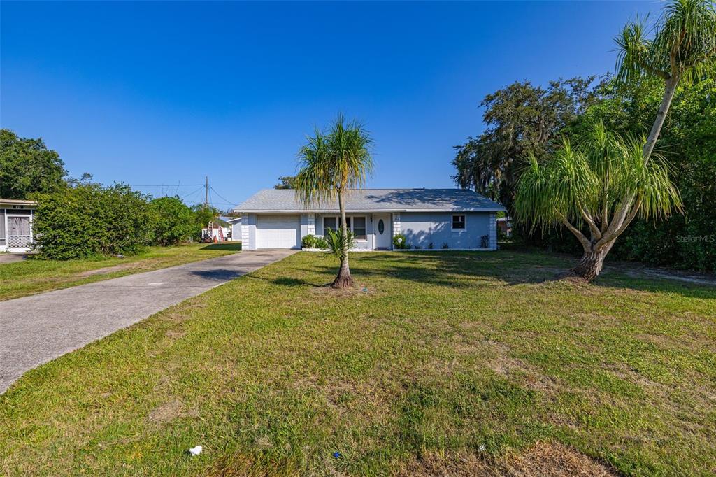 A swimming pool enclosed by a screened lanai sits next to a light blue house — 608 CHEROKEE CIRCLE, AVON PARK, FL