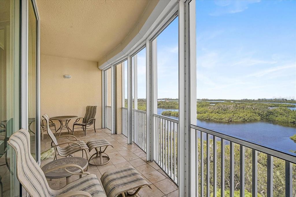 A tiled balcony features patio furniture and a screened-in view of a river and mangroves — 409 N POINT ROAD UNIT 803, OSPREY, FL