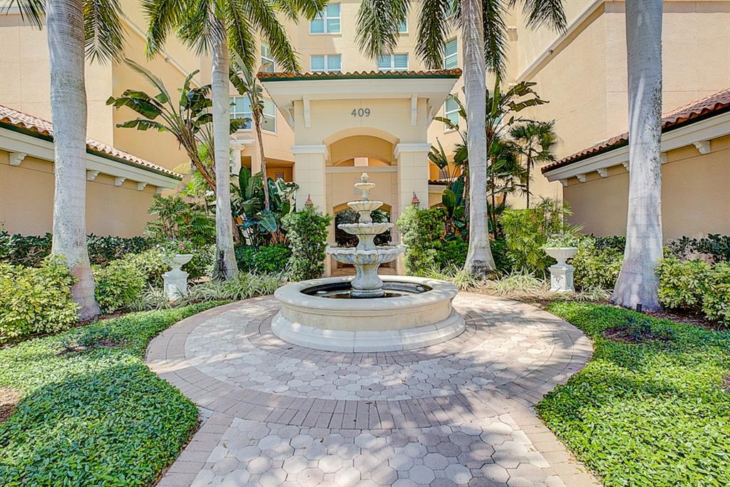 A tiered stone fountain sits in the center of a paved courtyard before a building entrance — 409 N POINT ROAD UNIT 803, OSPREY, FL