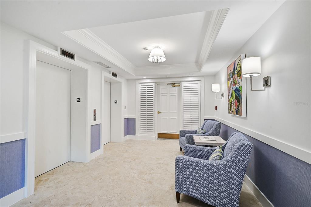 A hallway with two elevators, two patterned armchairs, and a white door with shutters — 409 N POINT ROAD UNIT 803, OSPREY, FL