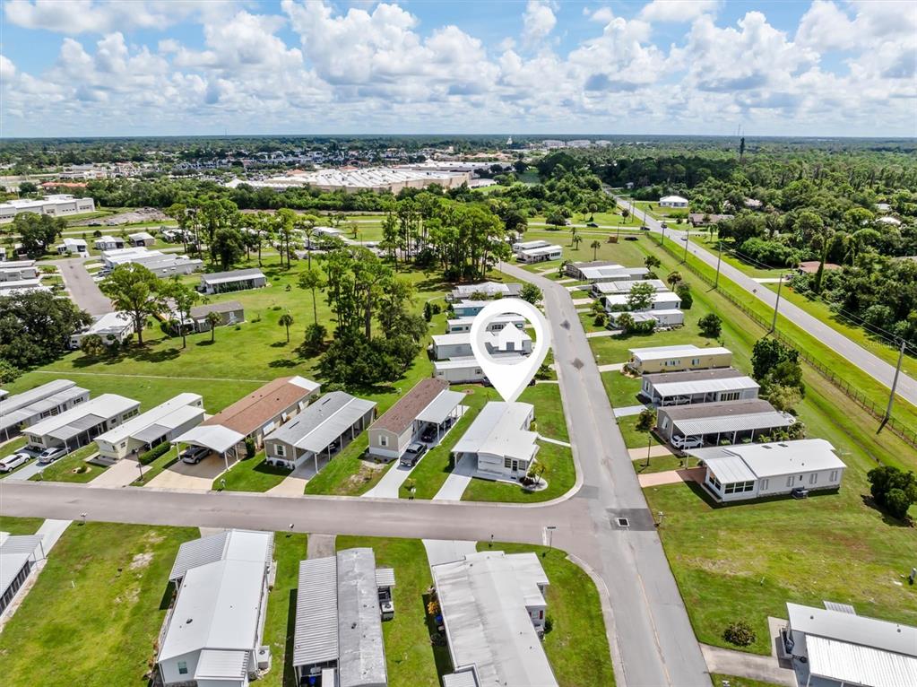 An aerial view shows a manufactured home community with several single-story houses and paved streets — 6704 HOEMI COURT, NORTH PORT, FL