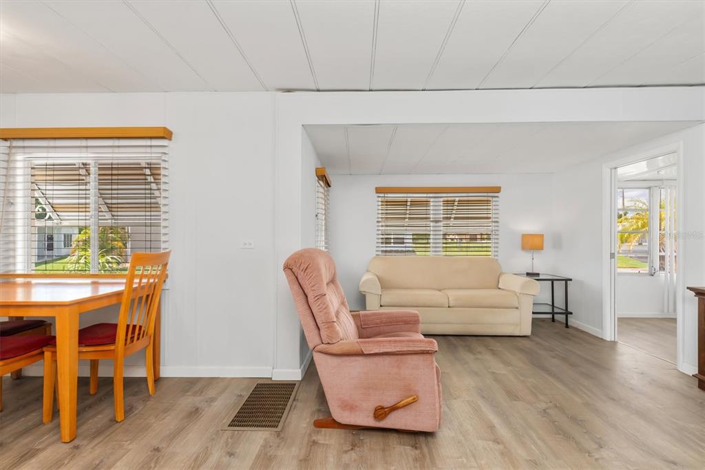 A living and dining area with light wood flooring, white walls, and a pink recliner — 6704 HOEMI COURT, NORTH PORT, FL