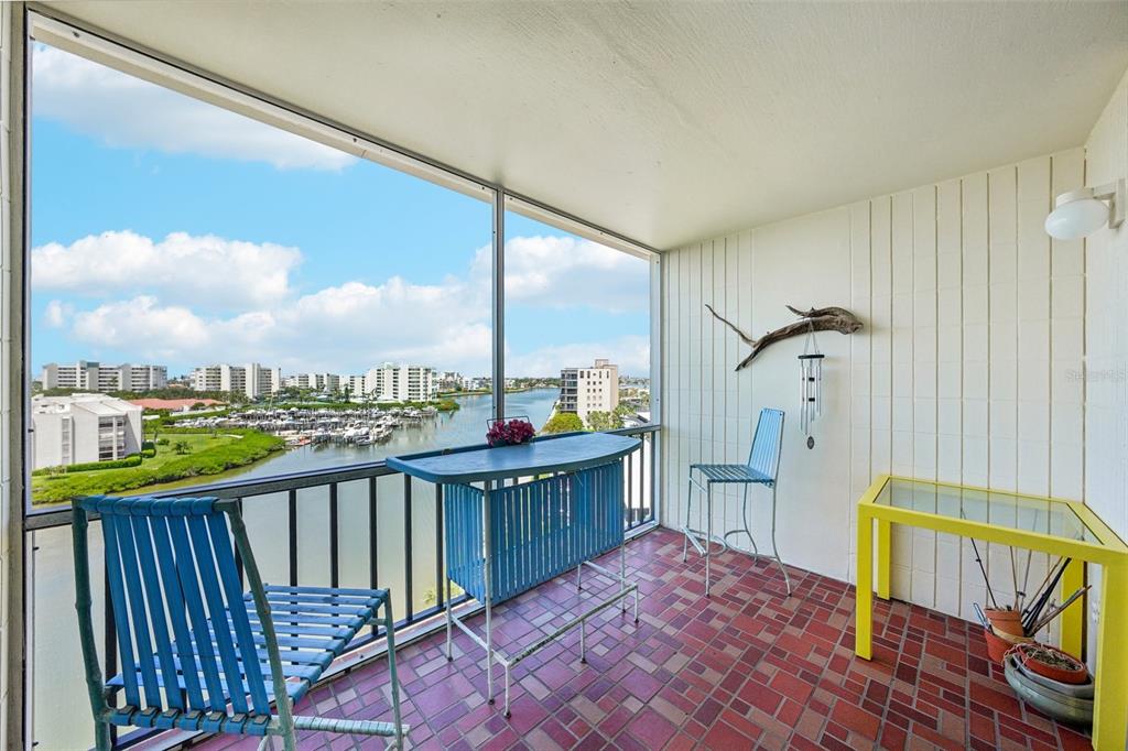 A screened balcony features a tiled floor, outdoor furniture, and a view of a marina — 7400 SUN ISLAND DRIVE S UNIT 802, SOUTH PASADENA, FL