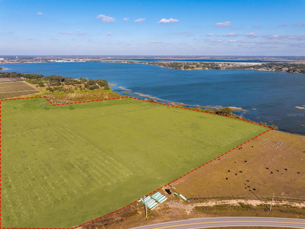An aerial view shows a large, grassy vacant lot outlined in red bordering a lake — OLD BERKLEY ROAD, AUBURNDALE, FL