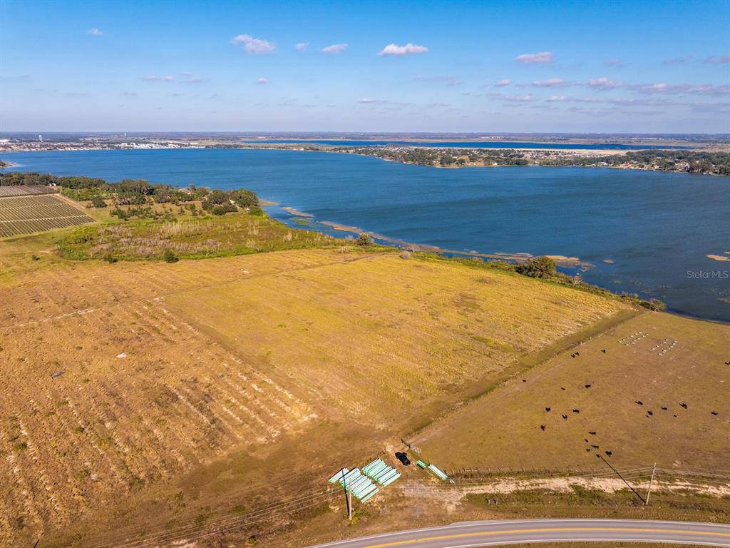 An aerial view shows a large, grassy field bordering a lake with a road nearby — OLD BERKLEY ROAD, AUBURNDALE, FL