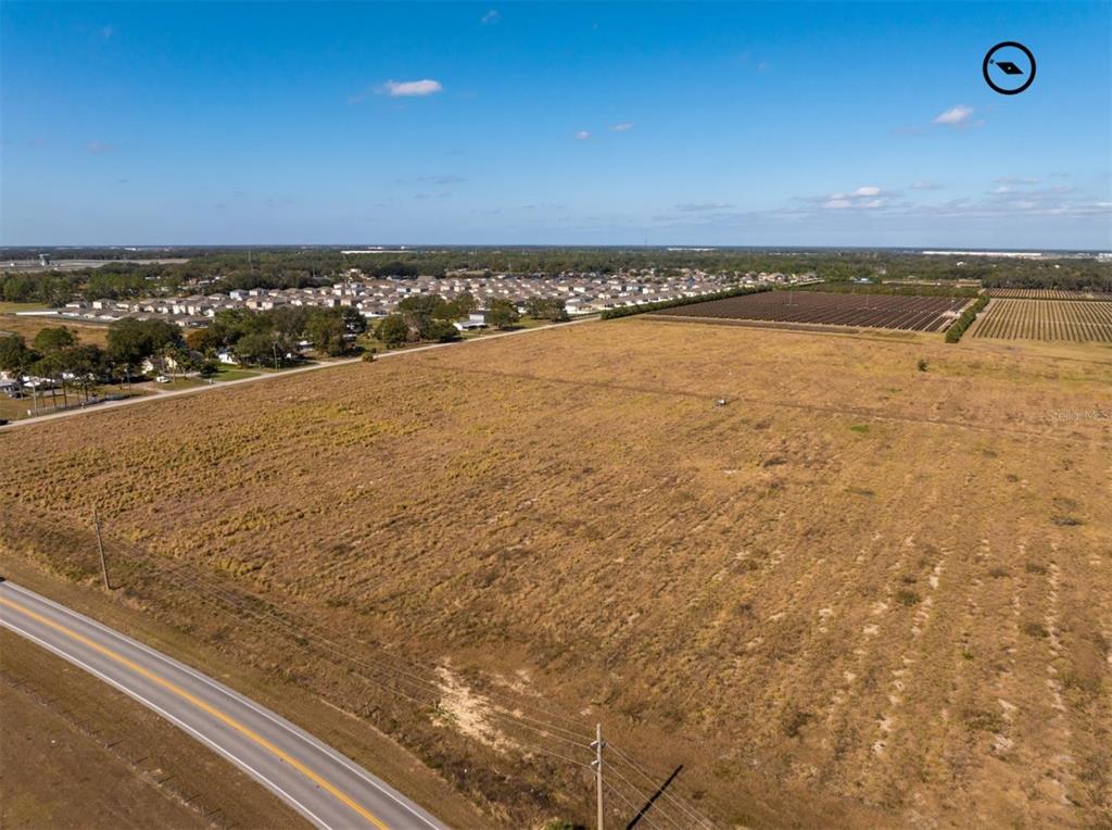 An aerial view shows a large, undeveloped grassy lot bordering a paved road — OLD BERKLEY ROAD, AUBURNDALE, FL