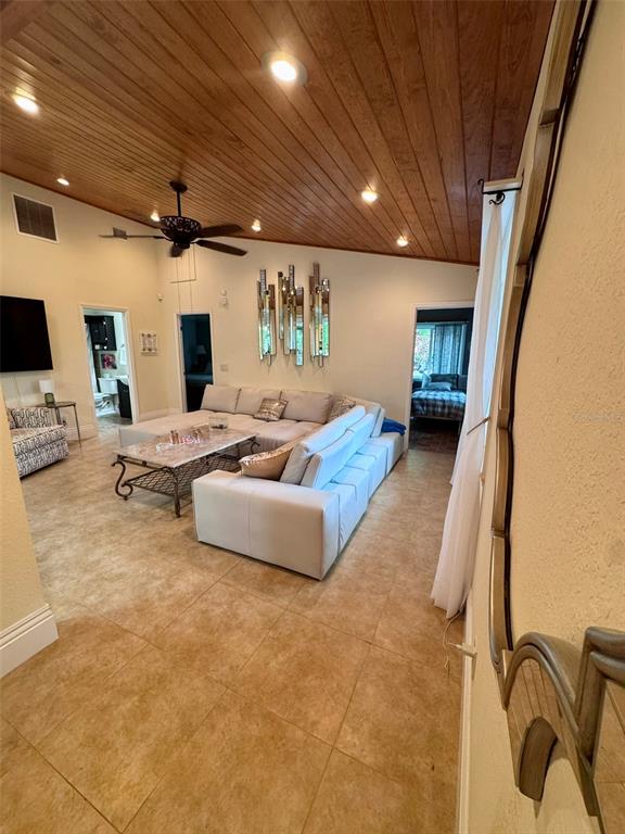 A living room features a wood-paneled vaulted ceiling, tile flooring, and a large sectional sofa — 4300 GULL COVE, NEW SMYRNA BEACH, FL