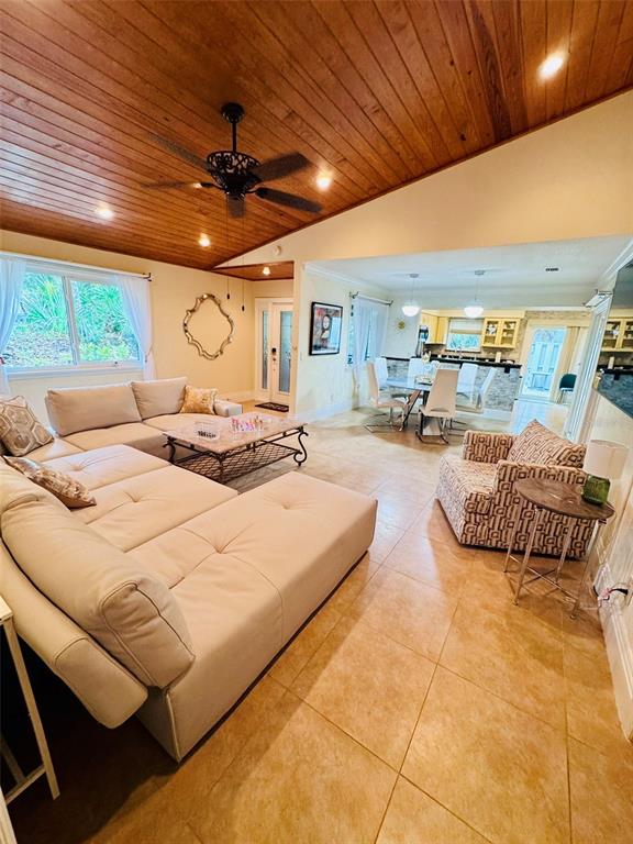 A living room with a wood-paneled vaulted ceiling, tile floors, and an open kitchen area — 4300 GULL COVE, NEW SMYRNA BEACH, FL