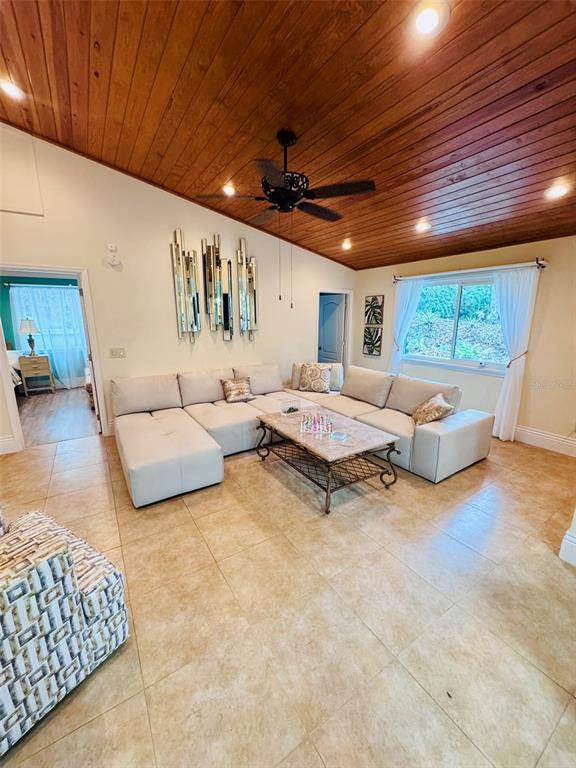 A living room features a sectional sofa, wood-paneled vaulted ceiling, and tile flooring — 4300 GULL COVE, NEW SMYRNA BEACH, FL