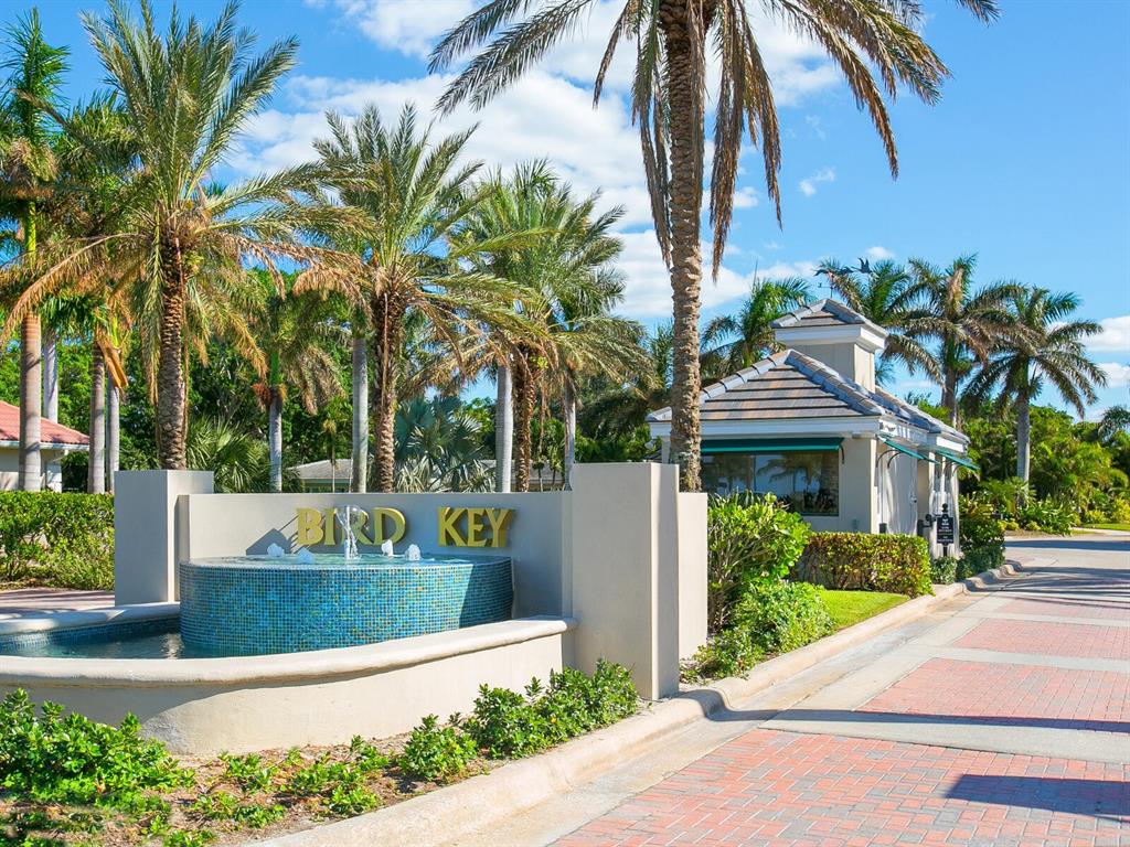 A gated entrance with a blue tiled fountain and palm trees at Bird Key — 509 SPOONBILL WAY, SARASOTA, FL