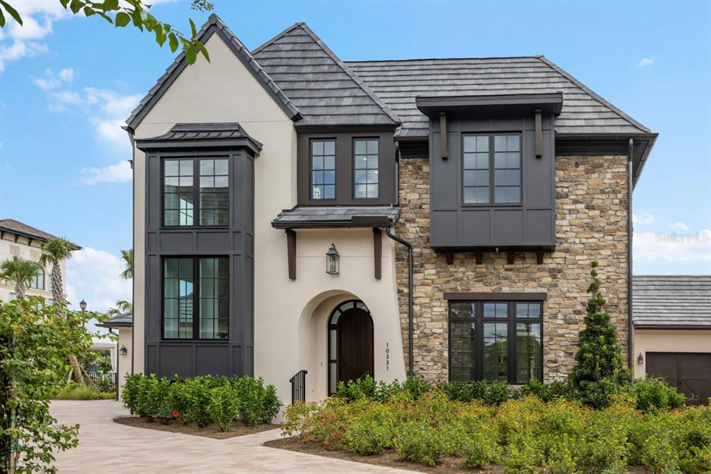 A two-story house features a stone and stucco exterior with dark trim and a tiled roof — 10331 WINTER SPARKLE CIRCLE, GOLDEN OAK, FL