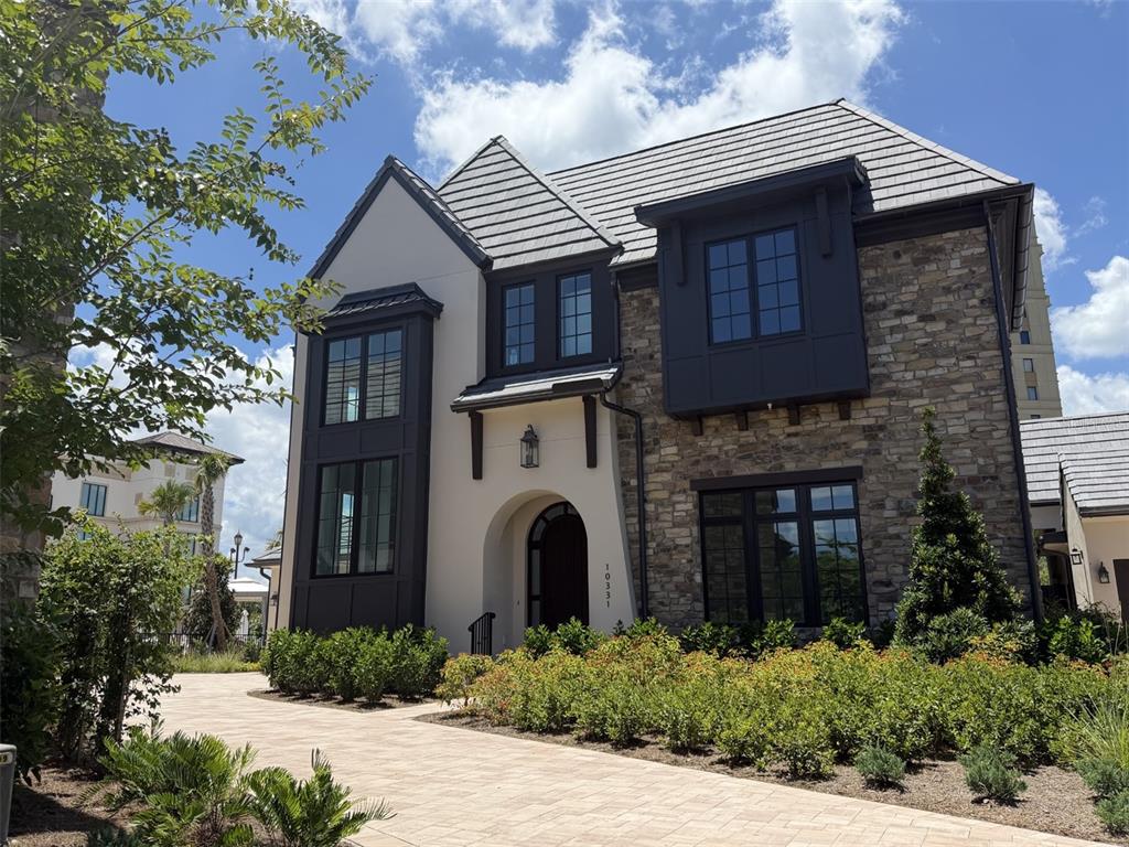 A two-story house features a stone and stucco exterior with dark-framed windows and a driveway — 10331 WINTER SPARKLE CIRCLE, GOLDEN OAK, FL