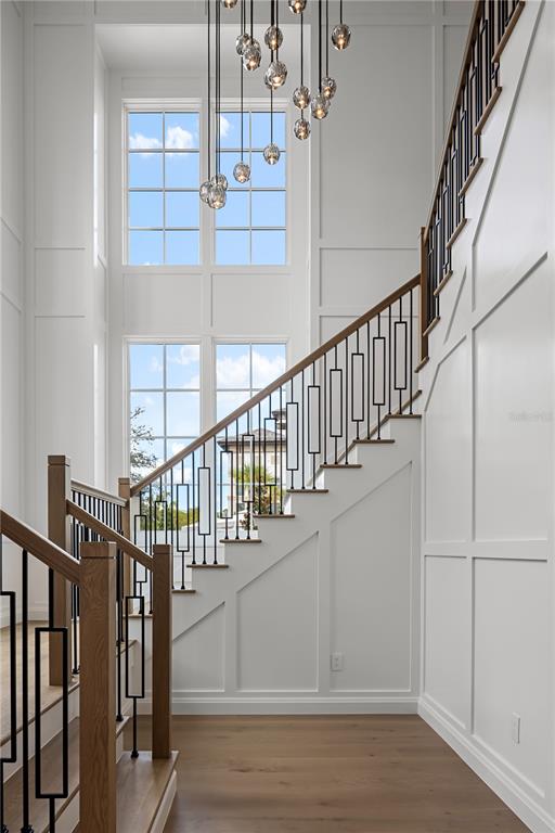 A bright foyer features a wooden staircase with black railings and a modern glass chandelier — 10331 WINTER SPARKLE CIRCLE, GOLDEN OAK, FL