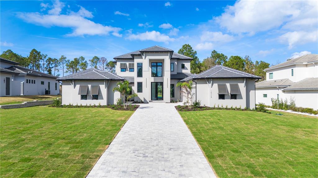 A modern two-story house with a gray tile roof, stucco exterior, and a central entryway — 16118 PENDIO DRIVE, MONTVERDE, FL