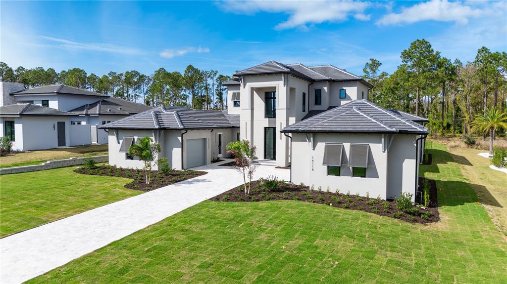 A two-story modern house with a gray exterior, tiled roof, and a paved driveway — 16118 PENDIO DRIVE, MONTVERDE, FL
