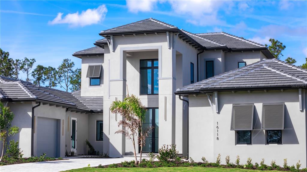 A modern two-story house with a gray stucco exterior, tiled roof, and a paved walkway — 16118 PENDIO DRIVE, MONTVERDE, FL