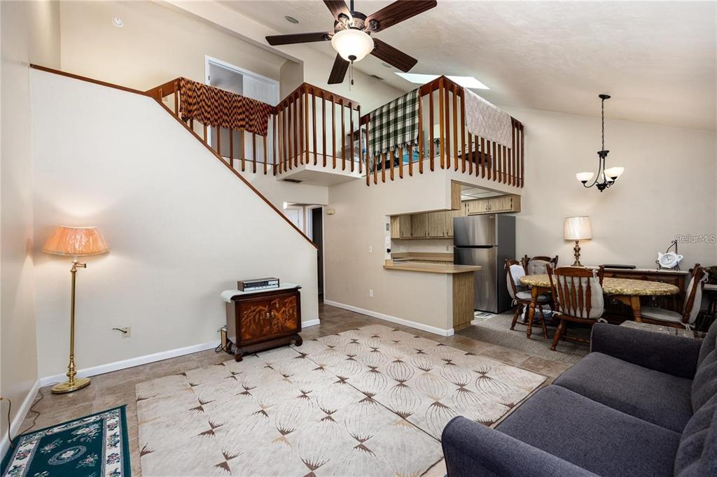 A living room with a loft, vaulted ceiling, tile flooring, and an adjacent dining area — 4704 SW 67TH TERRACE, GAINESVILLE, FL