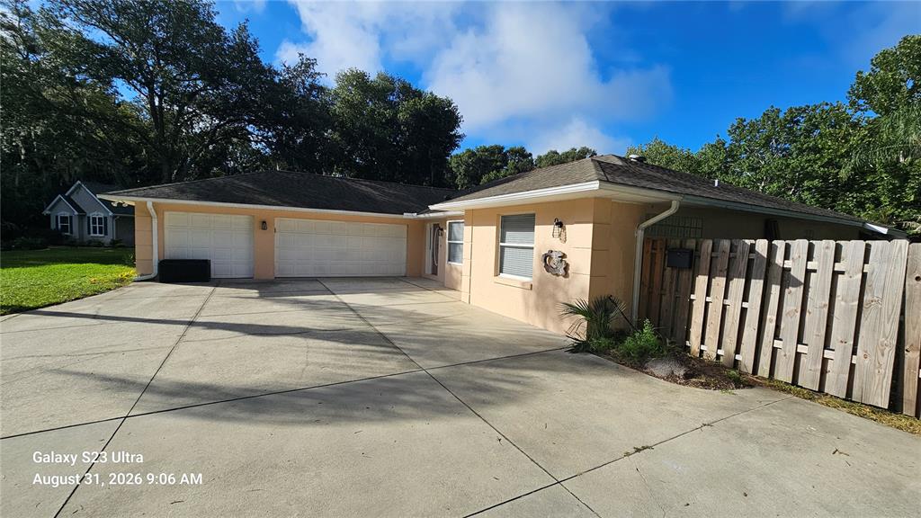 A peach-colored house features a two-car garage and a wooden privacy fence — 3998 DAKOTA CIRCLE, ORMOND BEACH, FL