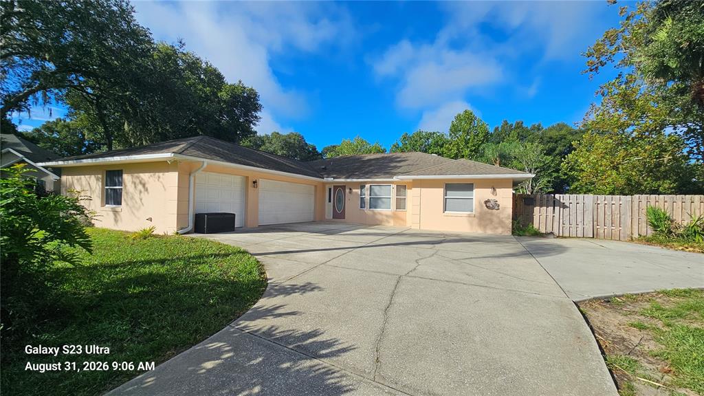 A single-story house with a two-car garage, a concrete driveway, and a wooden fence — 3998 DAKOTA CIRCLE, ORMOND BEACH, FL
