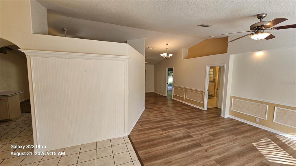 An interior view shows a living area with wood-look flooring, wainscoting, and a ceiling fan — 3998 DAKOTA CIRCLE, ORMOND BEACH, FL