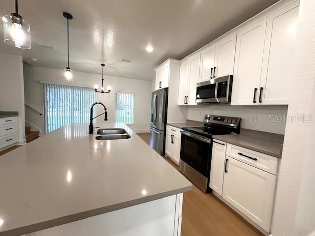 A modern kitchen features white cabinets, stainless steel appliances, and a large quartz-topped island — 250 E COLLINS STREET, UMATILLA, FL