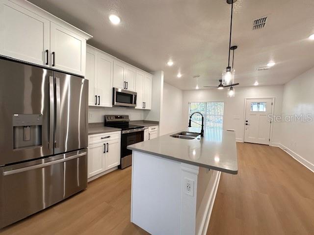 A modern kitchen features white cabinets, stainless steel appliances, and a central island with seating — 250 E COLLINS STREET, UMATILLA, FL