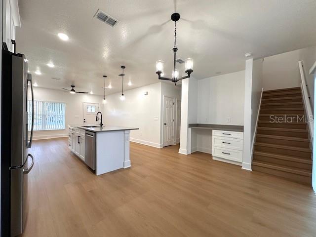 A kitchen with white cabinetry, a center island, and a staircase leading to an upper level — 250 E COLLINS STREET, UMATILLA, FL