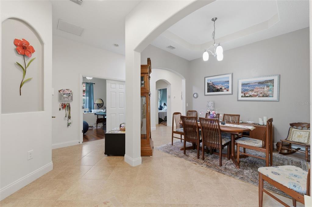 A dining room with a wooden table and chairs sits adjacent to an entryway hallway — 2732 DEVONOAK BOULEVARD, LAND O LAKES, FL