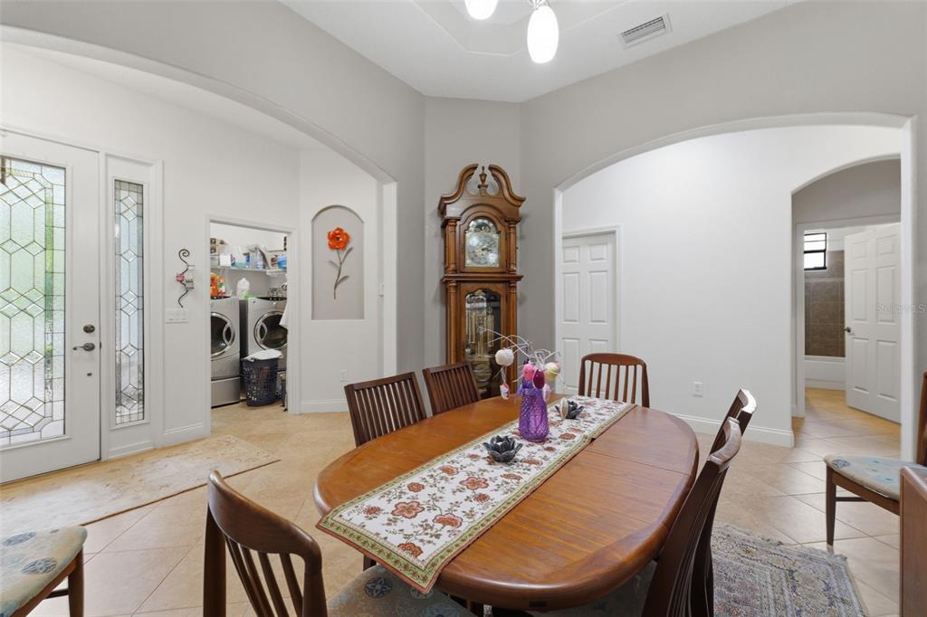 A dining room with tile floors, a wooden grandfather clock, and a laundry room visible — 2732 DEVONOAK BOULEVARD, LAND O LAKES, FL