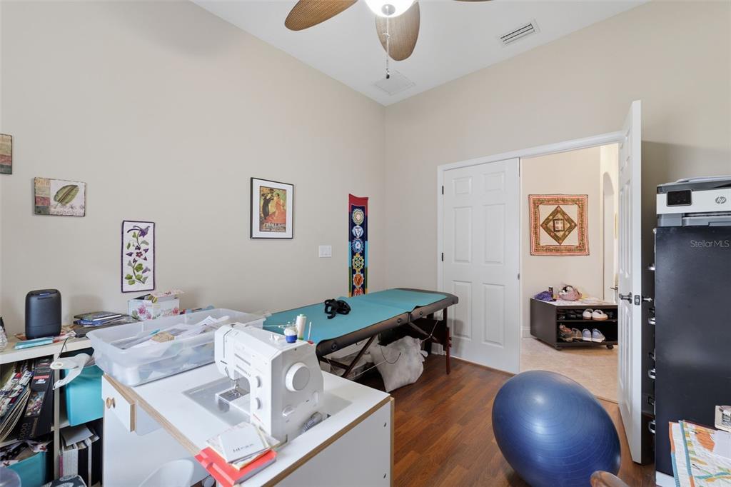 A craft room features a sewing machine, a massage table, a yoga ball, and wood flooring — 2732 DEVONOAK BOULEVARD, LAND O LAKES, FL